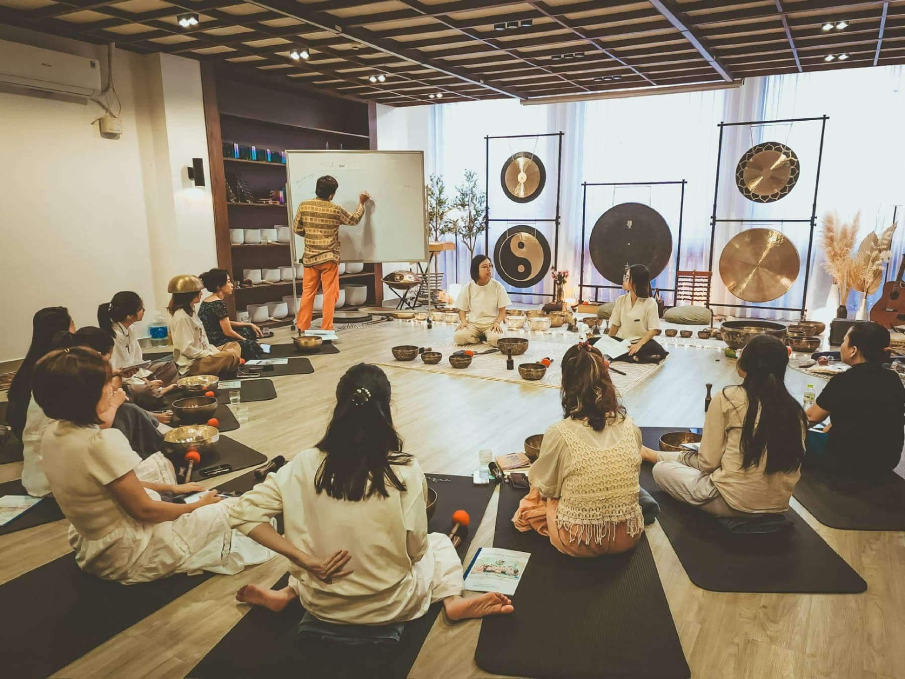 Students in a sound healing training class, seated with singing bowls and gongs